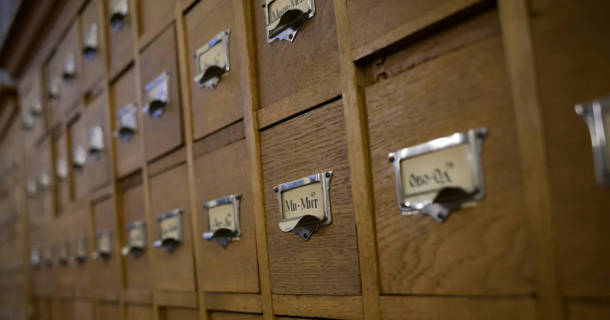 Rows of wooden library card catalogue drawers with metal label holders